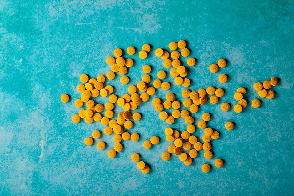Cortisol Levels and Stress: How to Test Your Adrenal Function close up of scattered yellow pills on a vibrant turquoise ba